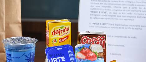 A basket of food items including a bottle of dafruta premium, a carton of Choco Mil, and various snacks.