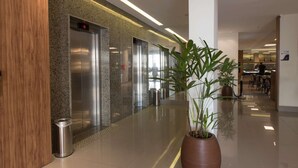 A modern hotel lobby with elevators, a potted plant, and a dining area in the background. - Days Inn Rio de Janeiro, Lapa (Rio de Janeiro)