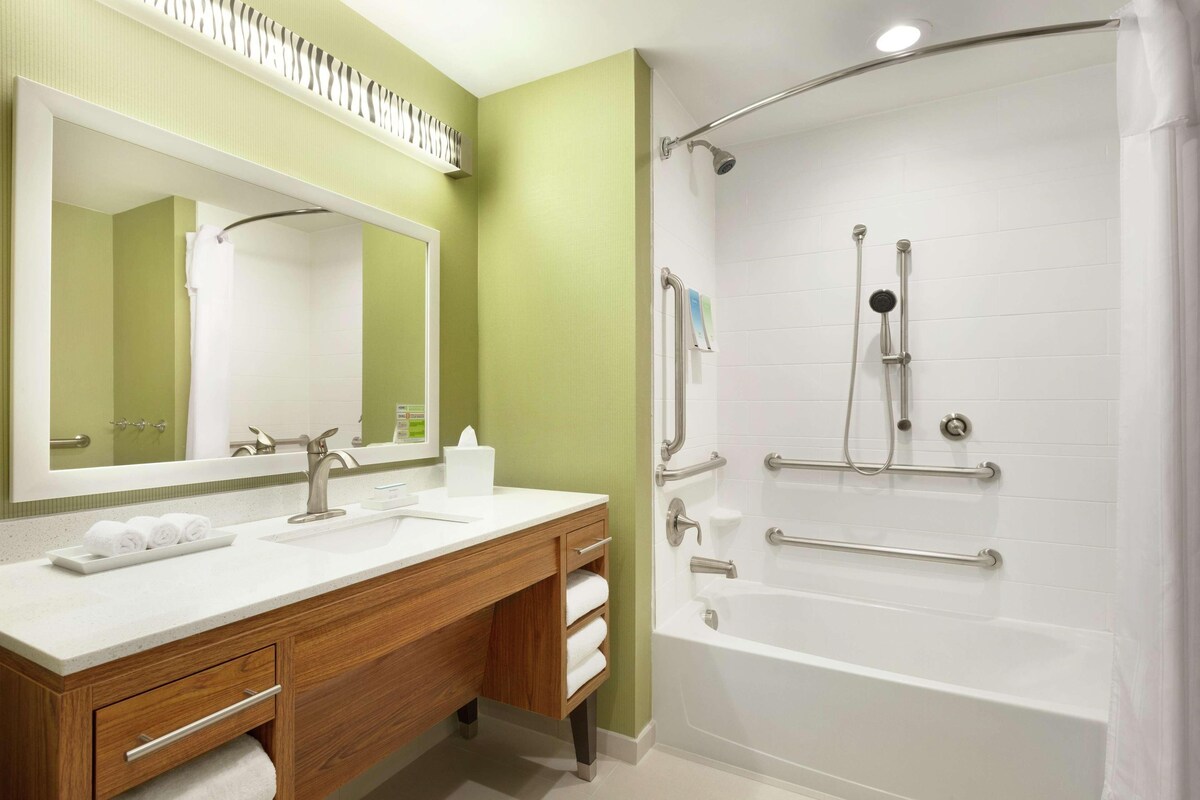 Un baño con lavamanos, espejo y ducha.