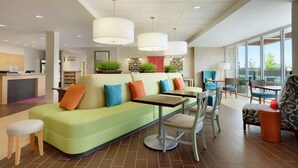 Eine moderne Hotelhalle mit einem grünen Sofa, Tischen, Stühlen und einer Rezeption.