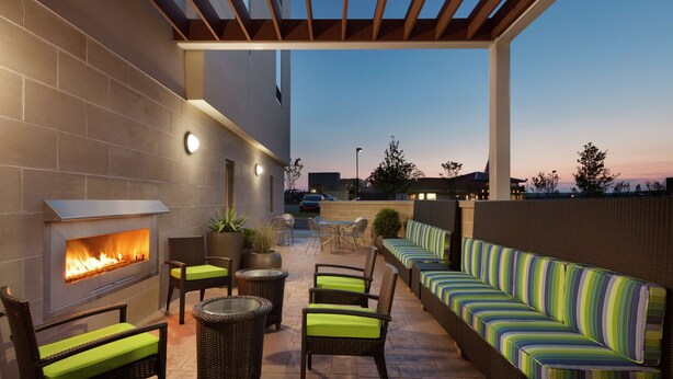Ein Patio im Freien mit Kamin, Korbmöbeln und einem gestreiften Sofa.