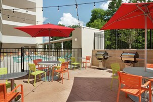 An outdoor patio with a pool, red umbrellas, and outdoor seating.
