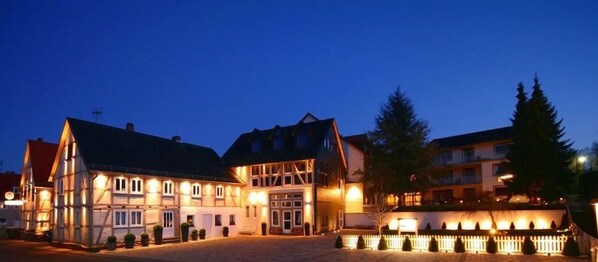 A traditional European building with a central entrance, surrounded by a cobblestone courtyard and a white picket fence. - Landhotel Kern (Bad Zwesten)