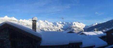 A snow-covered mountain village with wooden buildings and a clear blue sky.