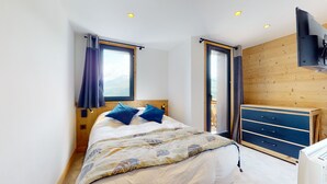 Un dormitorio con cama, armario de madera y ventana con cortinas.