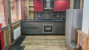 Una cocina moderna con detalles de madera, electrodomésticos de acero inoxidable y armarios rojos.