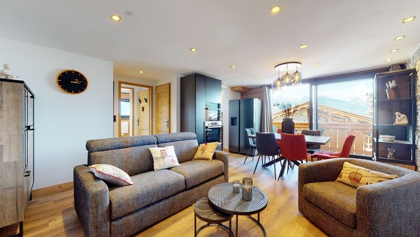 Una sala de estar moderna con sofá, sillones, una mesa de comedor y una cocina.