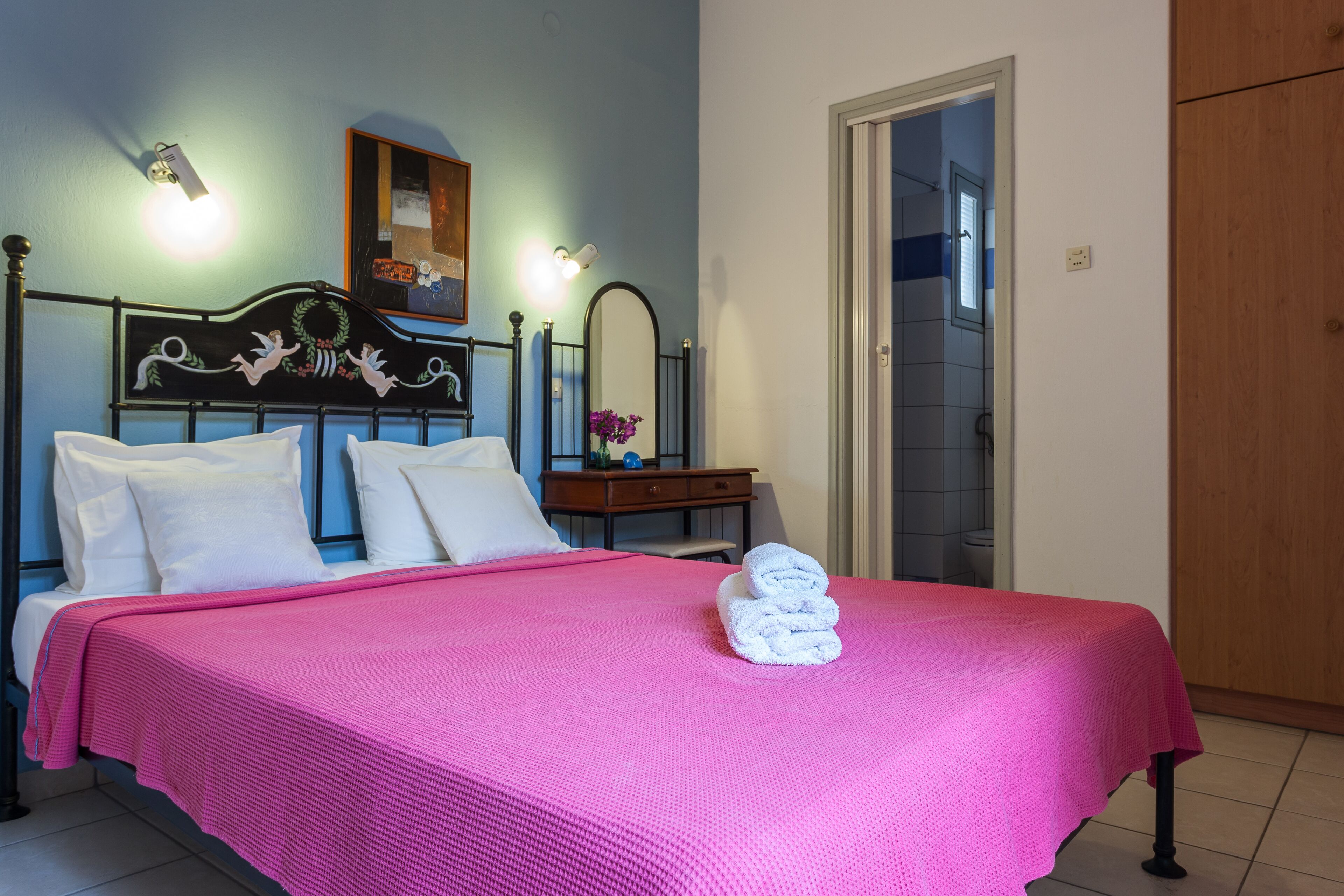 A bedroom with a bed, a nightstand, a mirror, and a door.
