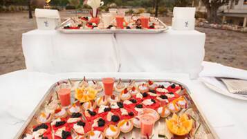Mesa servida con diversos aperitivos y bebidas, posiblemente para un bufé o fiesta.