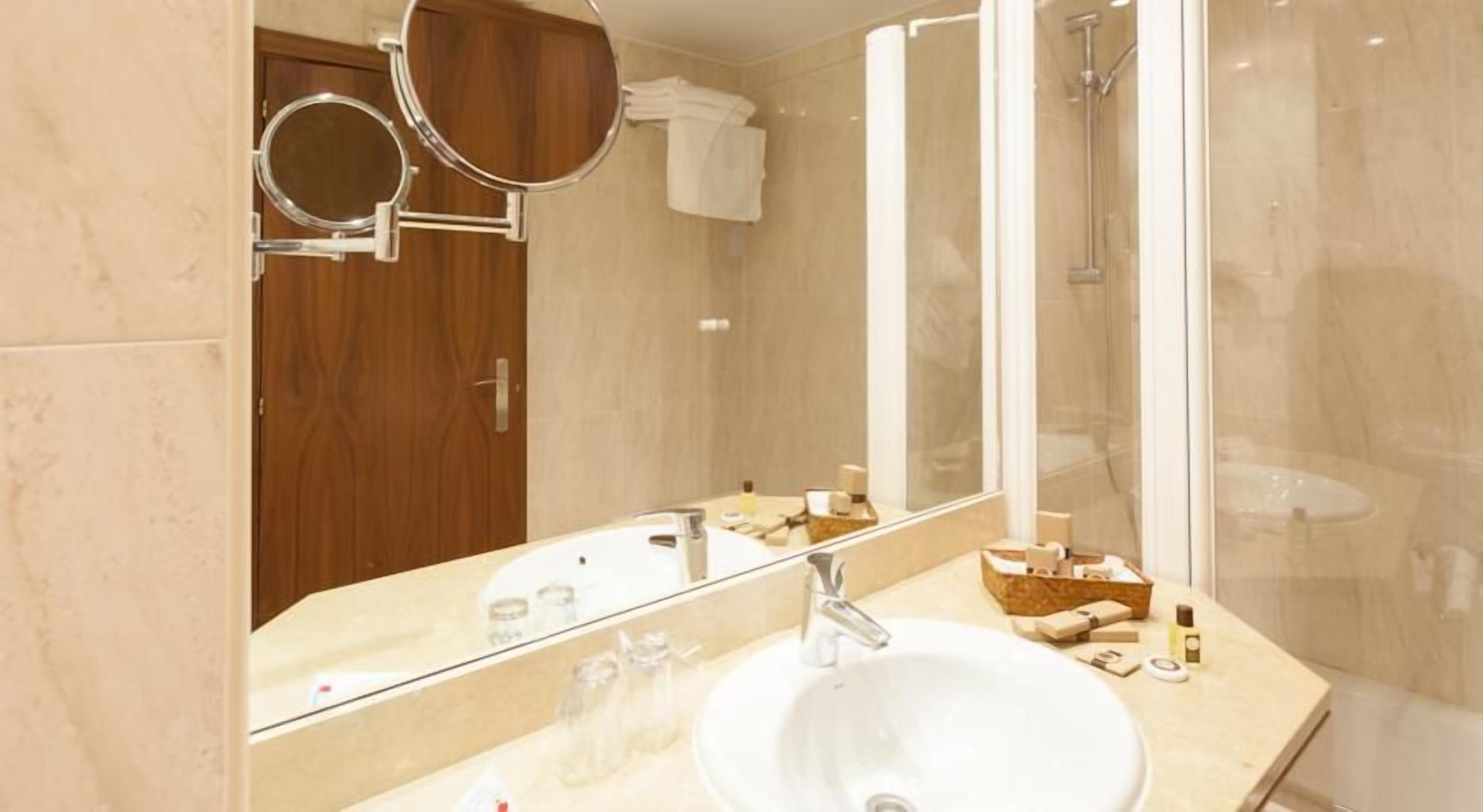 Un baño moderno con un espejo grande, un lavabo y una ducha.