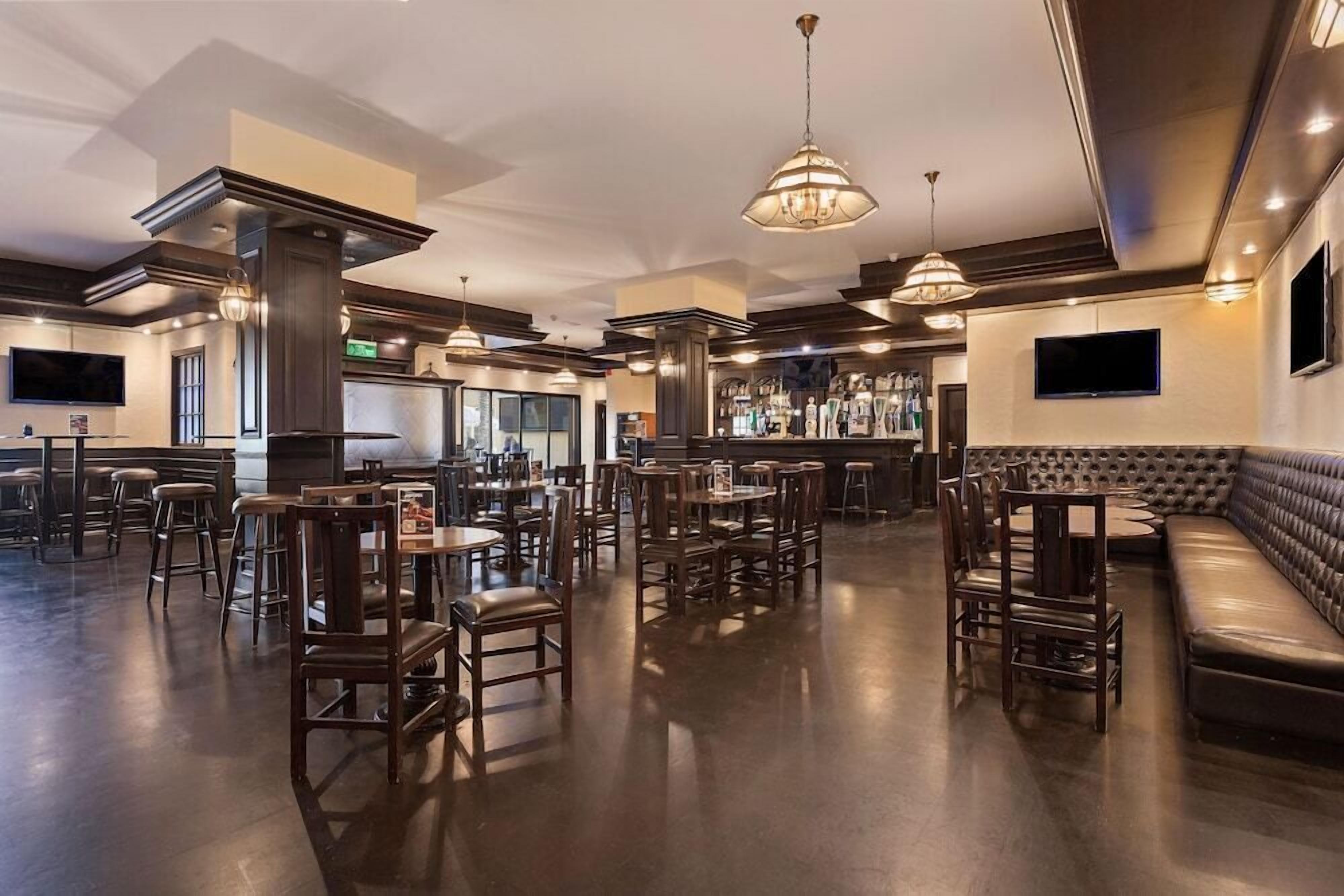 A spacious restaurant with high ceilings, multiple seating areas including tables and a sofa, and pendant lighting.
