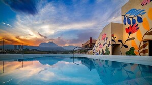 Une piscine offrant une vue dégagée sur les montagnes en arrière-plan et un ciel au coucher du soleil.