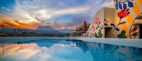 A swimming pool with a clear view of mountains in the background and a sunset sky.