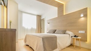 Une chambre d’hôtel moderne avec un grand lit, une table de chevet avec un téléphone et un mur décoratif en bois.