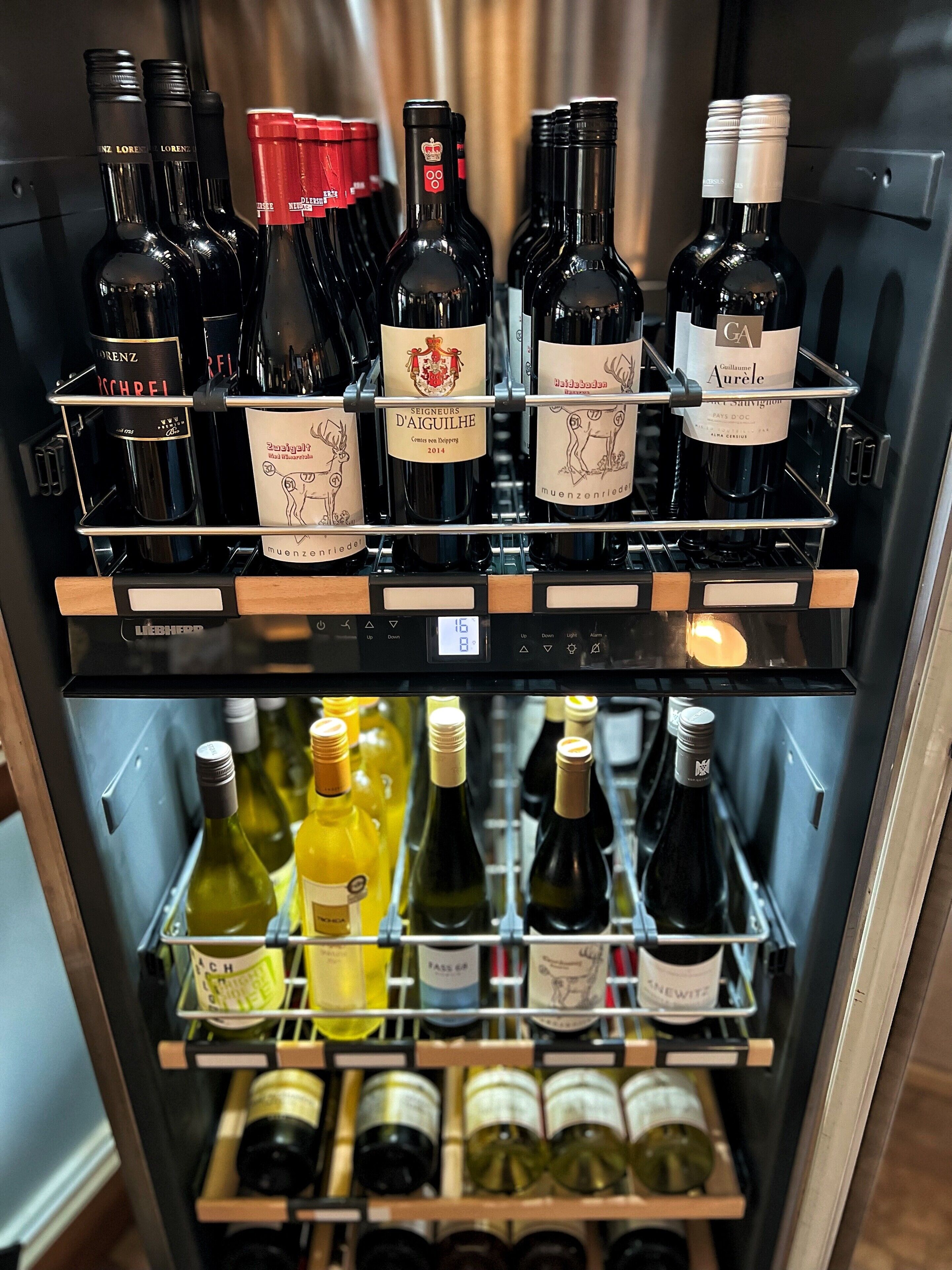 A wine refrigerator stocked with various bottles of wine, including brands like 'Lorenz' and 'Seigneurs D'Aiguille'.