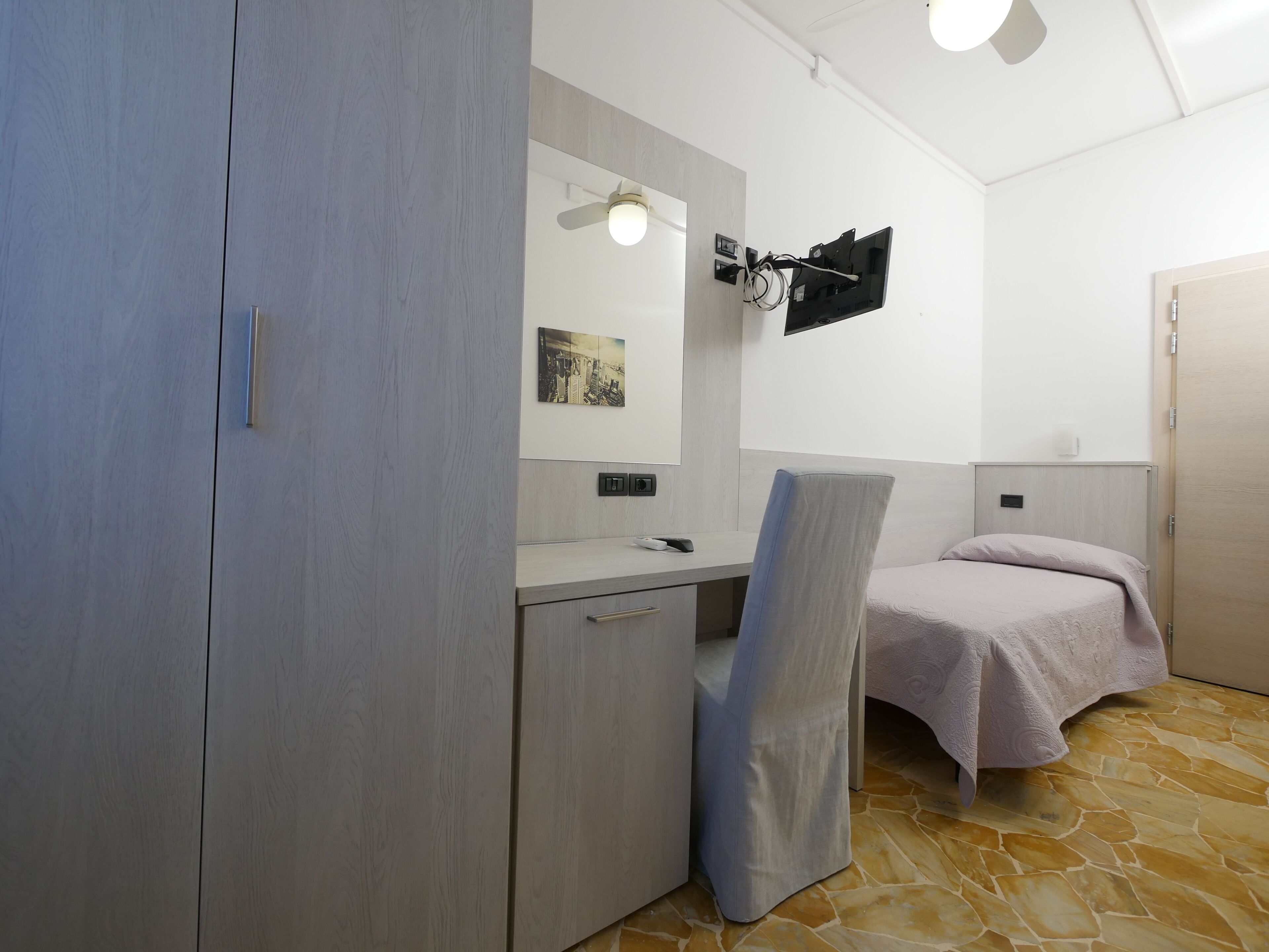 A modern bathroom with a vanity, a mirror, a ceiling fan, and a bed with a towel.