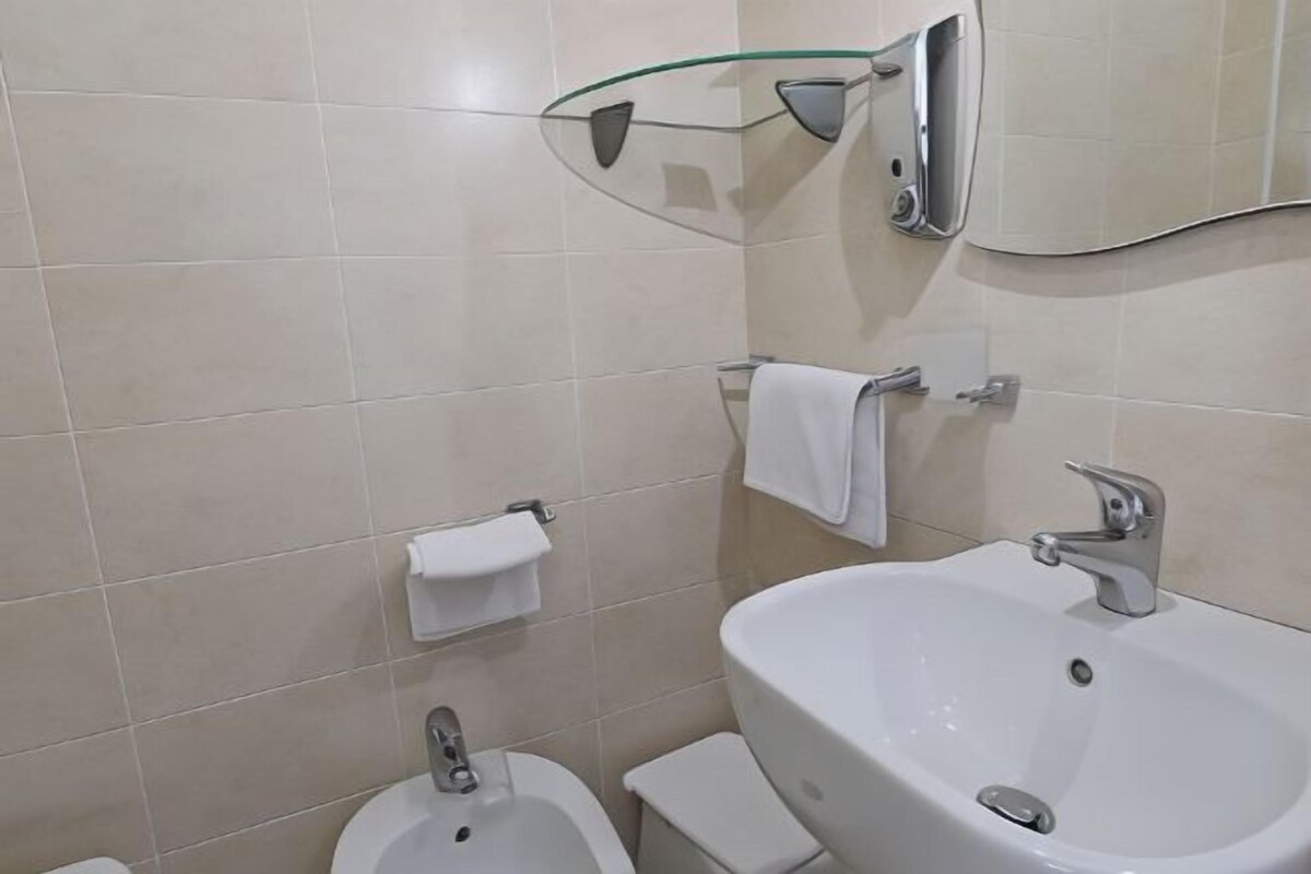 A bathroom with a sink, toilet, and bidet.