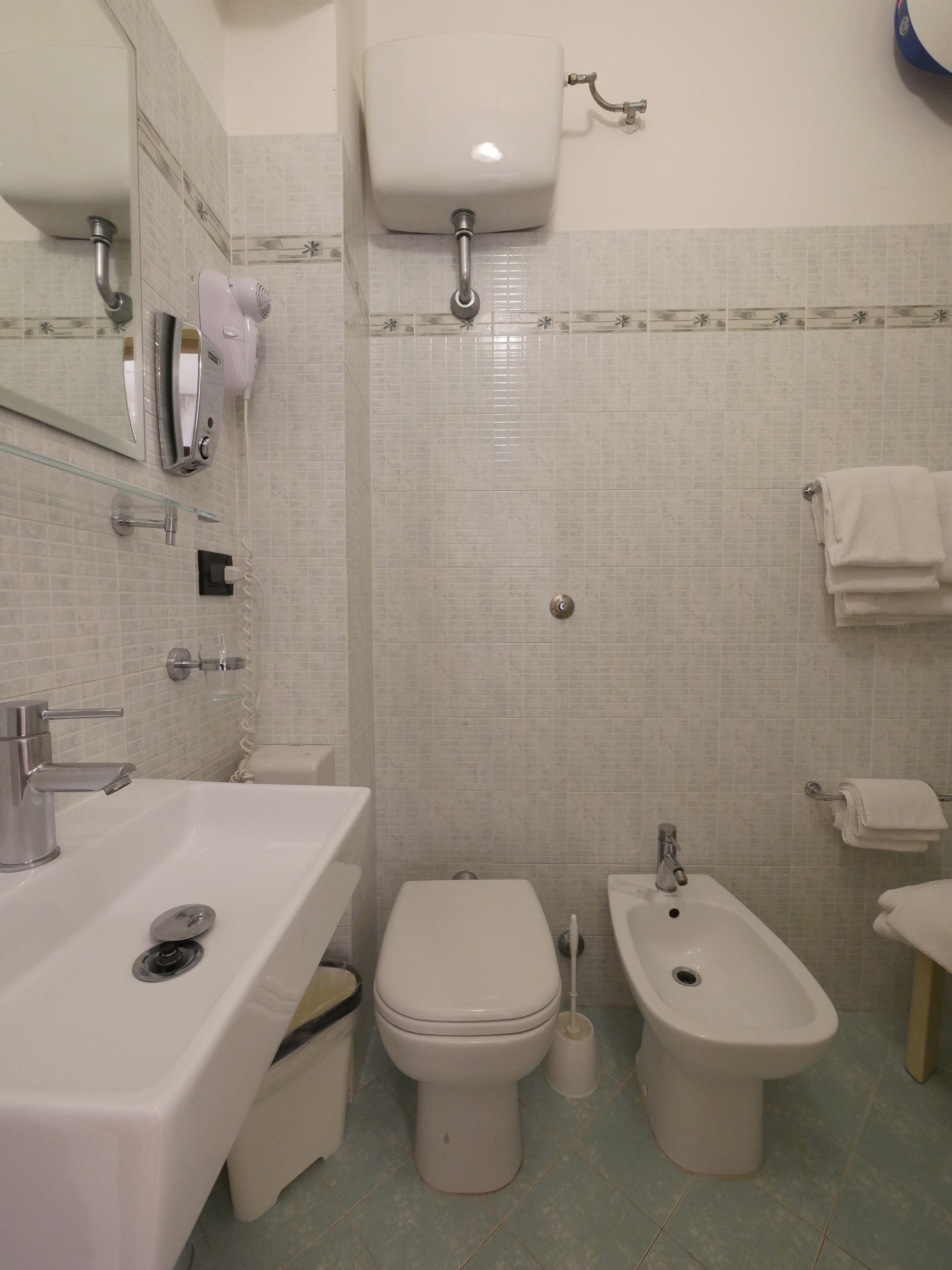 A bathroom with a sink, toilet, bidet, and a mirror.