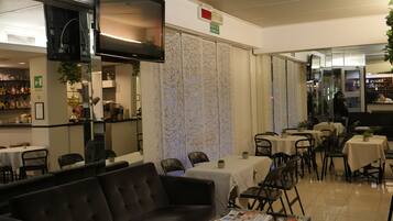 A modern interior with a sofa, tables, and chairs arranged for dining and relaxation.