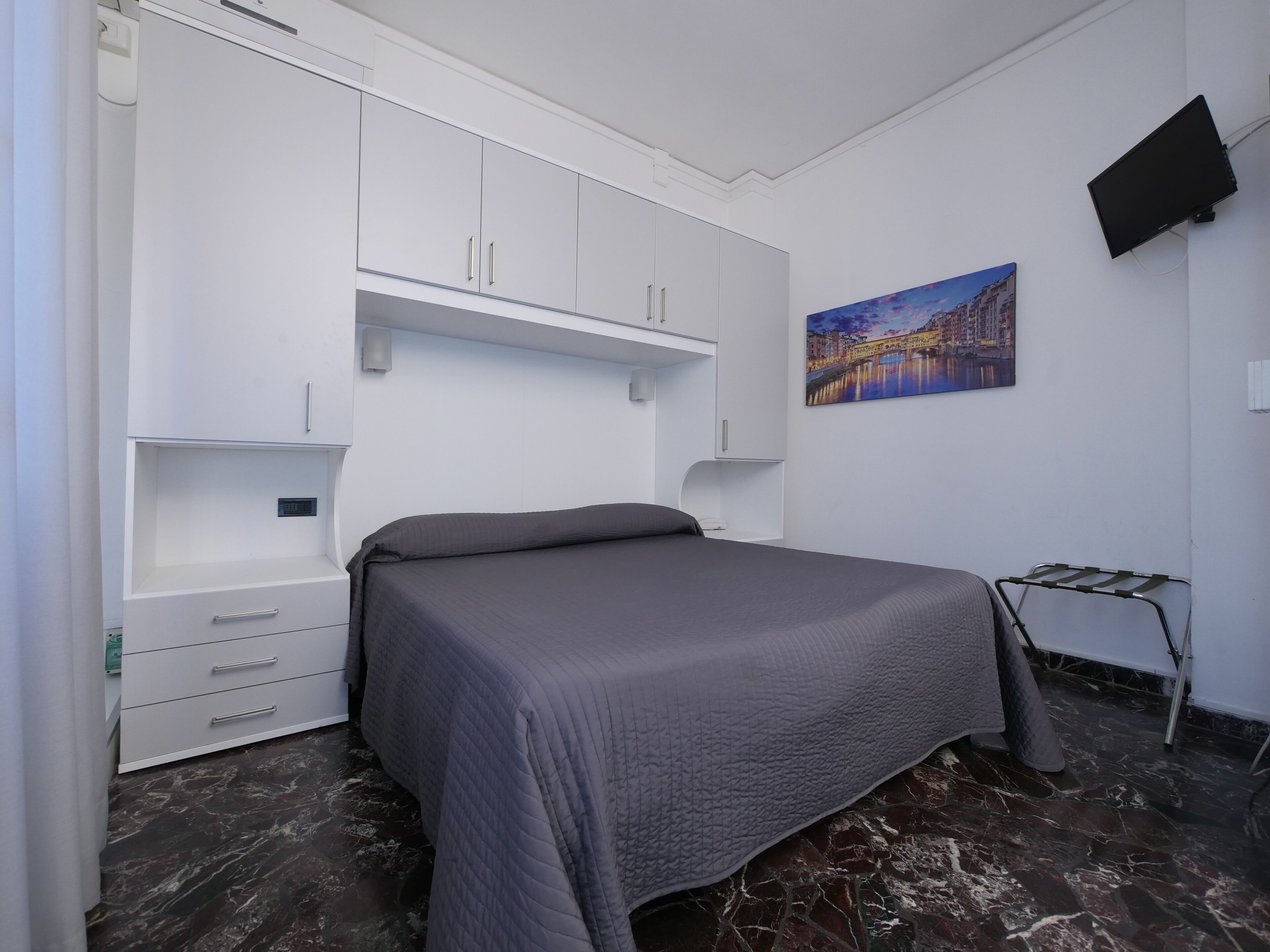 Un dormitorio con cama, armario blanco y un cuadro en la pared.