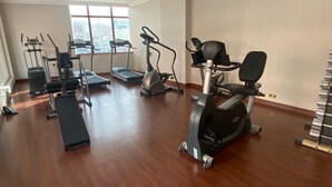 A spacious gym with various cardio machines, a bench, and a treadmill. - Royal Qatar Hotel (Doha)
