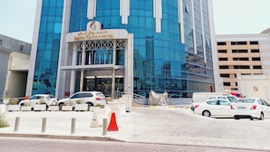 A modern hotel with a curved facade, large glass windows, and a prominent entrance with a sign. - Royal Qatar Hotel (Doha)