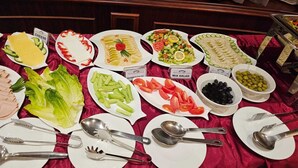A buffet table with various dishes including cheese, hummus salad, and mixed salad. - Royal Qatar Hotel (Doha)