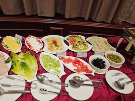 Una mesa de bufé con diversos platos, incluyendo queso, ensalada de hummus y ensalada mixta.
