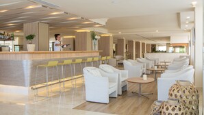 A modern hotel lobby with a bar area, seating arrangements, and a reception desk.