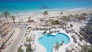 A resort with a large pool, beach, and ocean view.