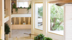 A multi-level interior with a central staircase, wooden paneling, and potted plants.