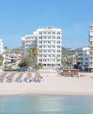 A beachfront hotel with multiple floors, a sandy beach in the foreground, and a clear blue sky. - Hotel Sabina & Suites (Son Servera)