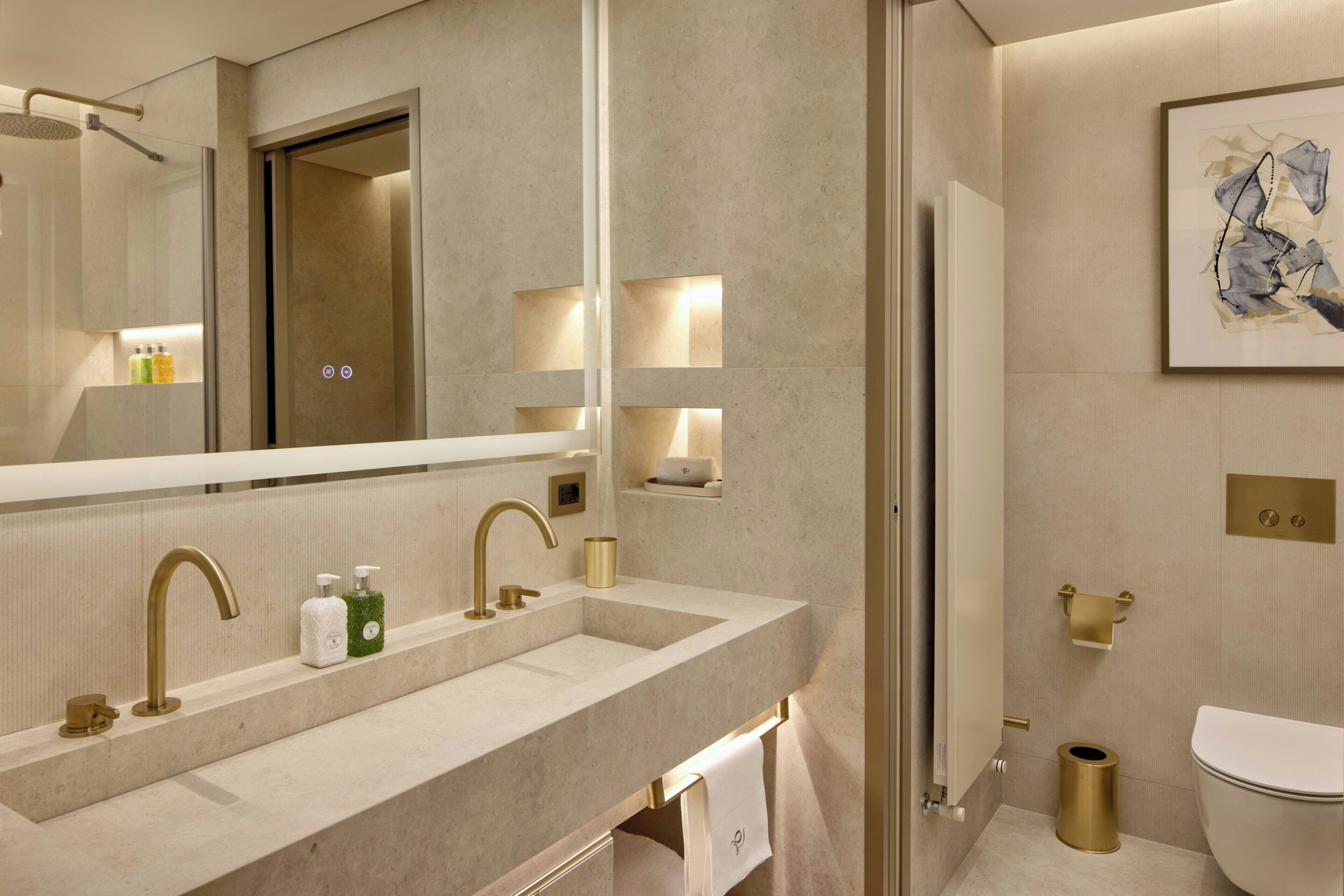 Un baño moderno con un espejo grande, lavamanos dobles y un inodoro.