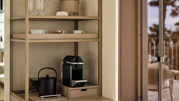 A shelf with a kettle, coffee maker, cups, and glasses.