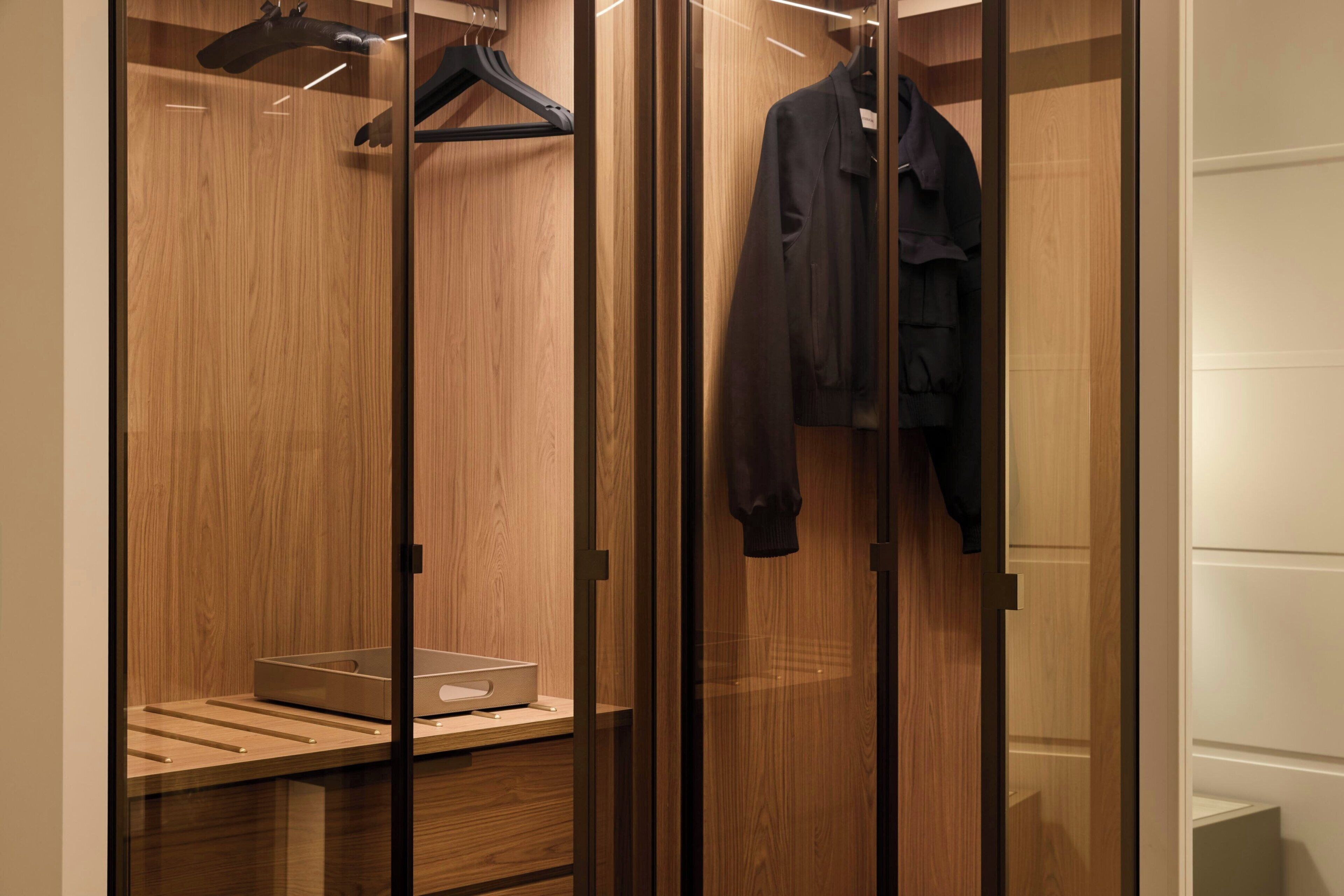 A walk-in closet with wooden paneling, a hanging rack, and a shelf with a storage box.
