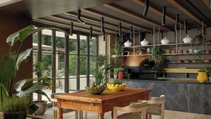 A modern kitchen with wooden cabinetry, a marble countertop, and a dining area with a wooden table and chairs. - Principessa Forte dei Marmi, Autograph Collection (Forte dei Marmi)