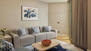 A modern living room with a grey sofa, a coffee table, and a painting on the wall.