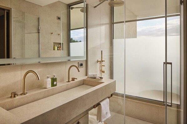 Un baño moderno con lavamanos doble, un espejo grande, cabina de ducha de vidrio y vistas a través de la puerta.