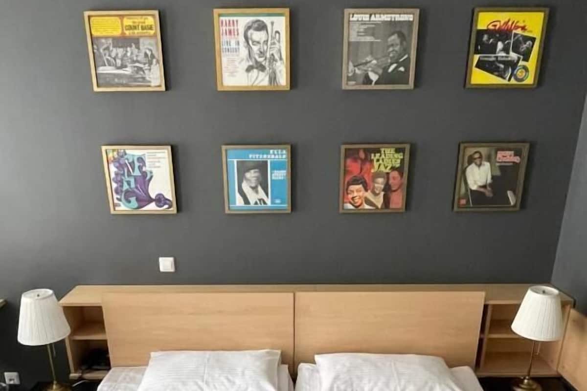 A hotel room with a large bed, two bedside tables with lamps, and a wall decorated with framed posters.
