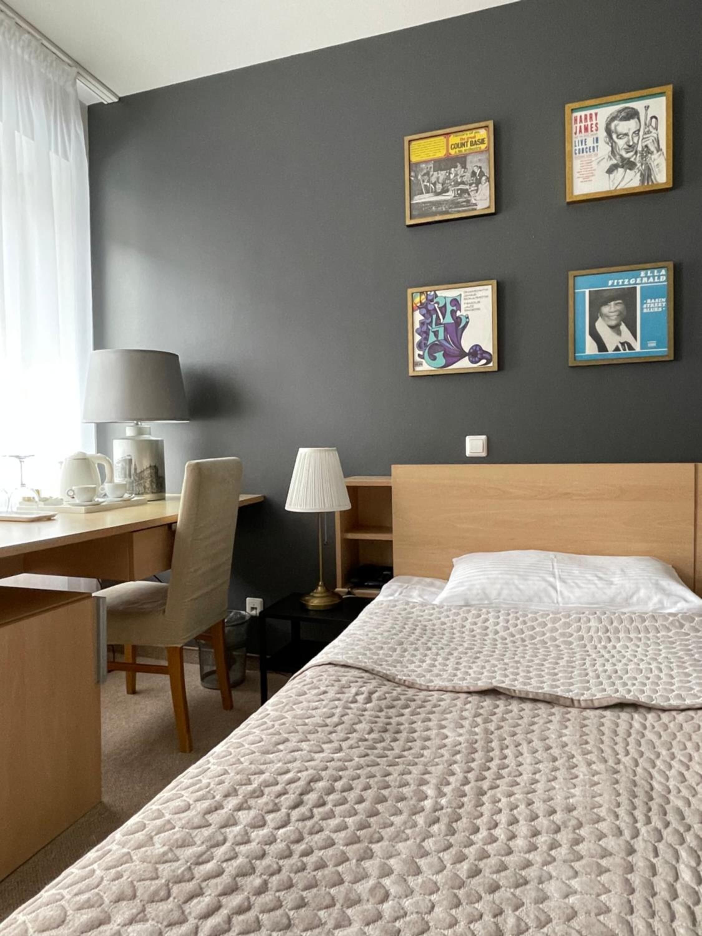 Ein Hotelzimmer mit Bett, Schreibtisch, Stuhl und Wandbildern.
