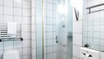 A modern bathroom with a glass-enclosed shower, a white toilet, and a large bathtub.