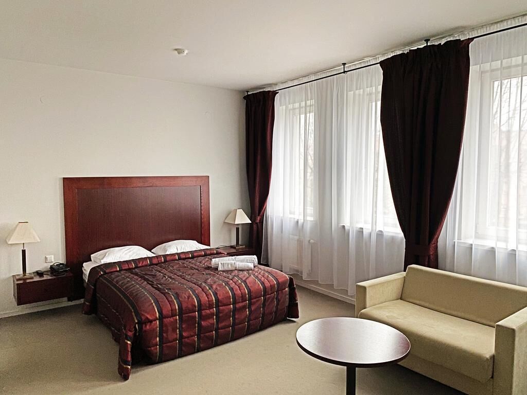 Et hotelværelse med en stor seng, en sofa, et lille bord og gardiner.