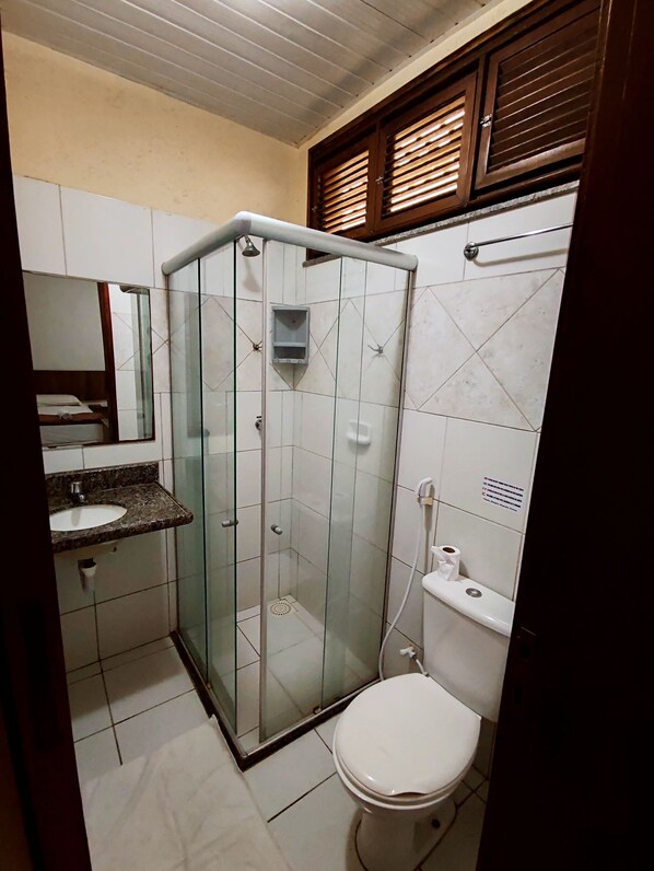 Un baño con ducha de vidrio, inodoro y lavabo con encimera de mármol.