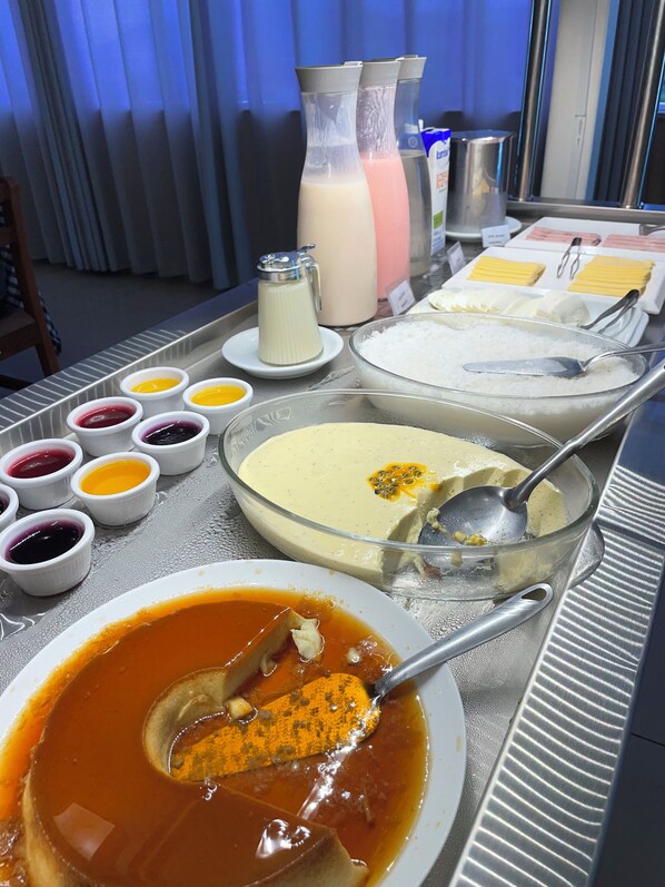 Una mesa de buffet con diversos alimentos, incluyendo un tazón grande de sopa, varios recipientes pequeños de salsas y un jarro de leche.