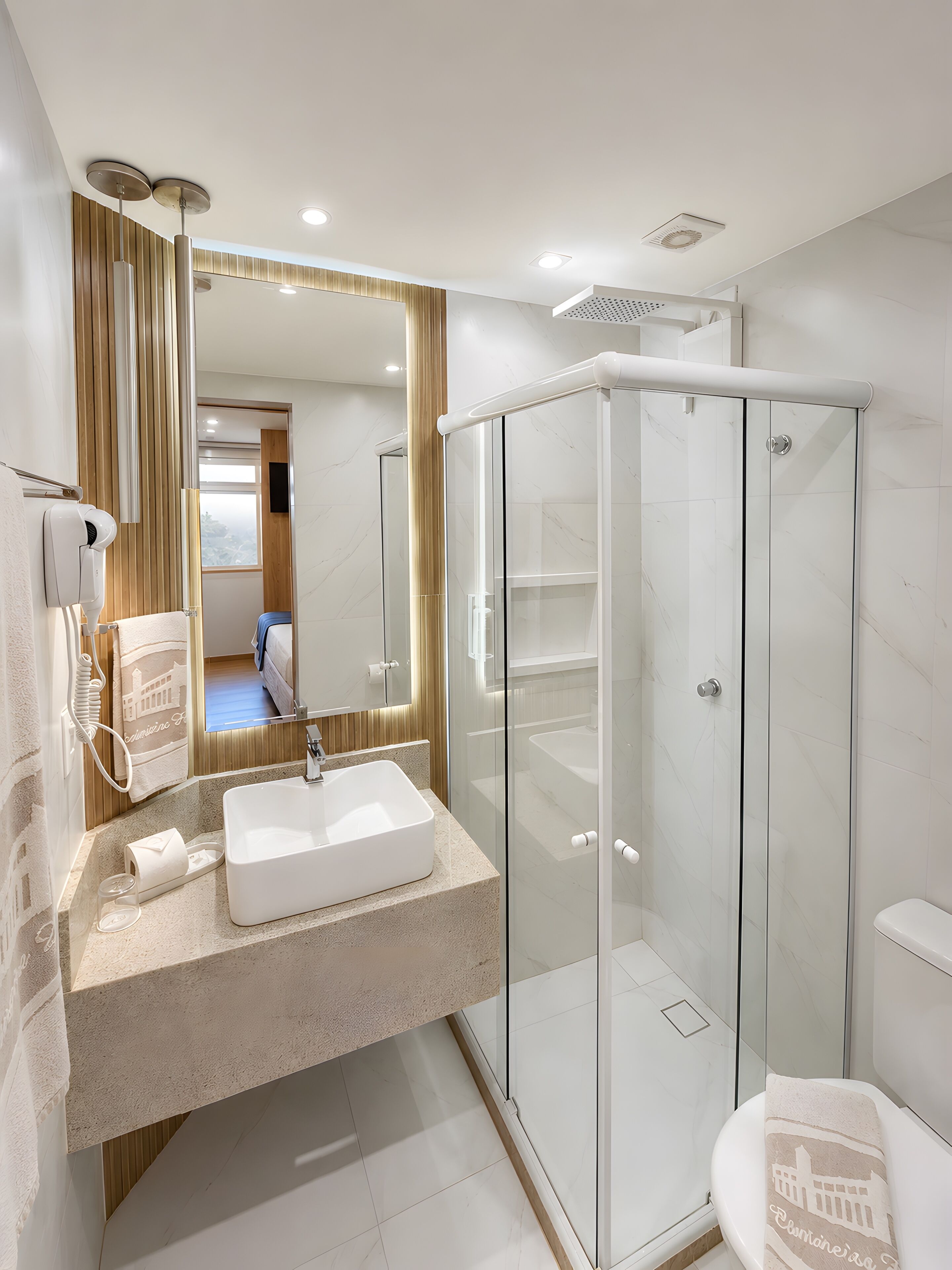 A modern bathroom with a glass-enclosed shower, a white sink, and a toilet.