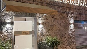 Fachada de hotel de piedra con letreros iluminados.