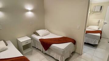 Habitación de hotel con dos camas, una mesita de noche, un espejo y un calentador de pared.