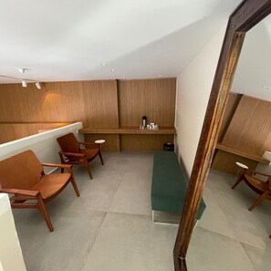 A modern room with a wooden slatted wall, a green bench, and wooden chairs. - Hotel Cantareira (Niteroi)