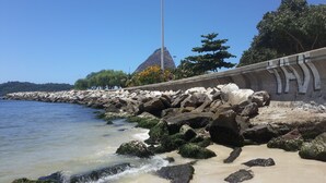 Uma área costeira com costa rochosa, uma estrutura alta e céu azul límpido.