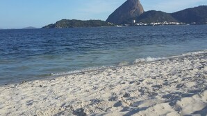 Uma praia com areia branca e uma grande formação rochosa ao fundo.